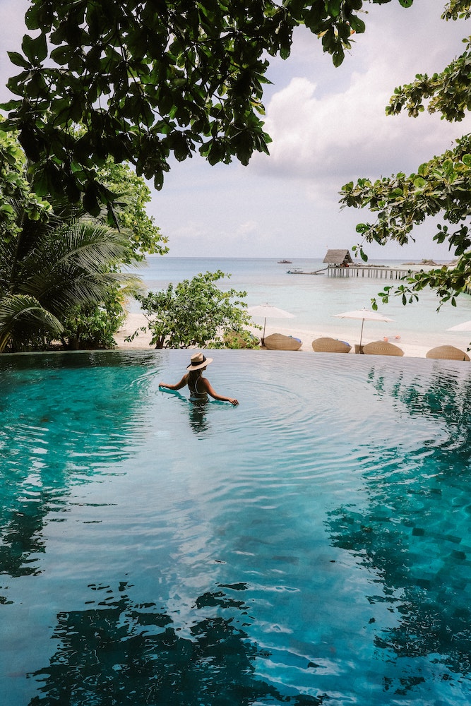 Woman in an infinity pool looking out to a beach